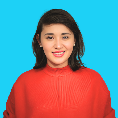 Portrait de Manshuk Ahmetzhan, spécialiste RH et fondatrice de PHRcert, qui partage son parcours avec le TDAH dans « Comprendre commence à la maison », souriante en chandail rouge devant un fond bleu.